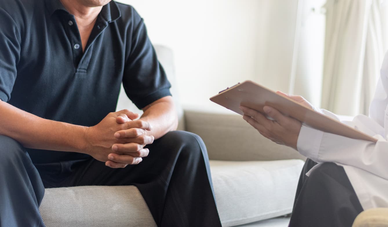 Doctor physician consulting with male patients in hospital exam room stock photo