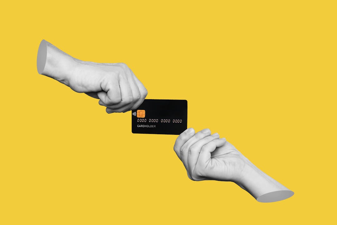 Black debit card changing hands against a yellow background stock image