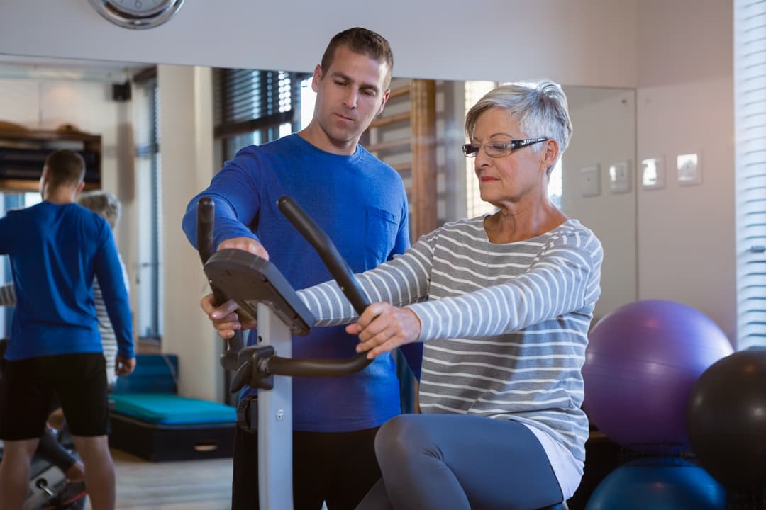 Physiotherapist showing workout record on exercise bike