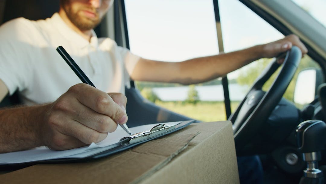 male driver taking notes from behind the wheel stock image
