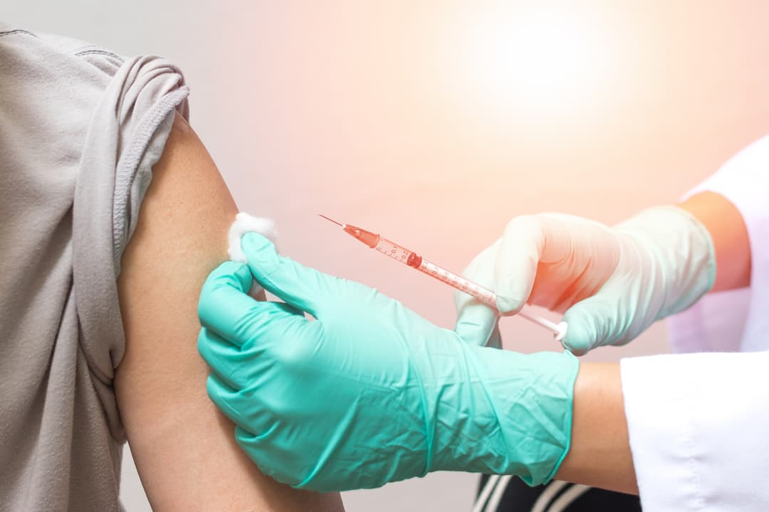 Hands of doctor or nurse in medical gloves injecting a shot to a man patient stock photo