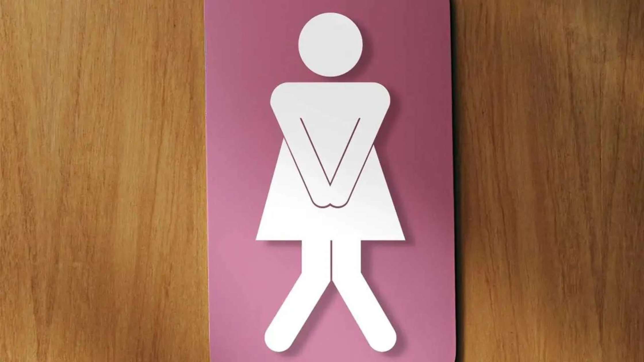 A women's restroom sign that has been modified to show the stick figure woman needing to use the toilet