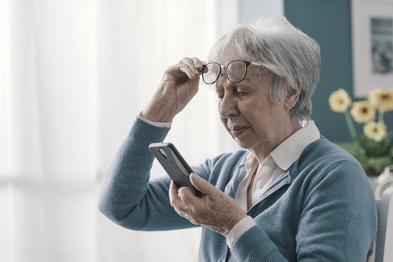 elderly woman with glasses having difficulty reading her phone stock image