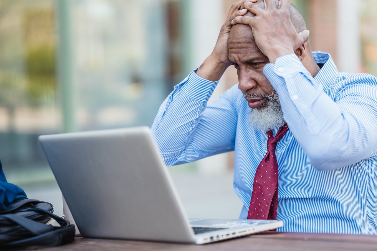 bearded man holding his head in confusion looking at his laptop stock image