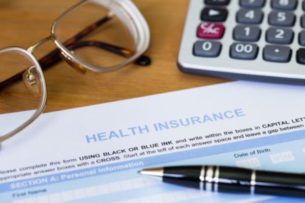 Health insurance form on a table with pen, calculator and glasses stock image